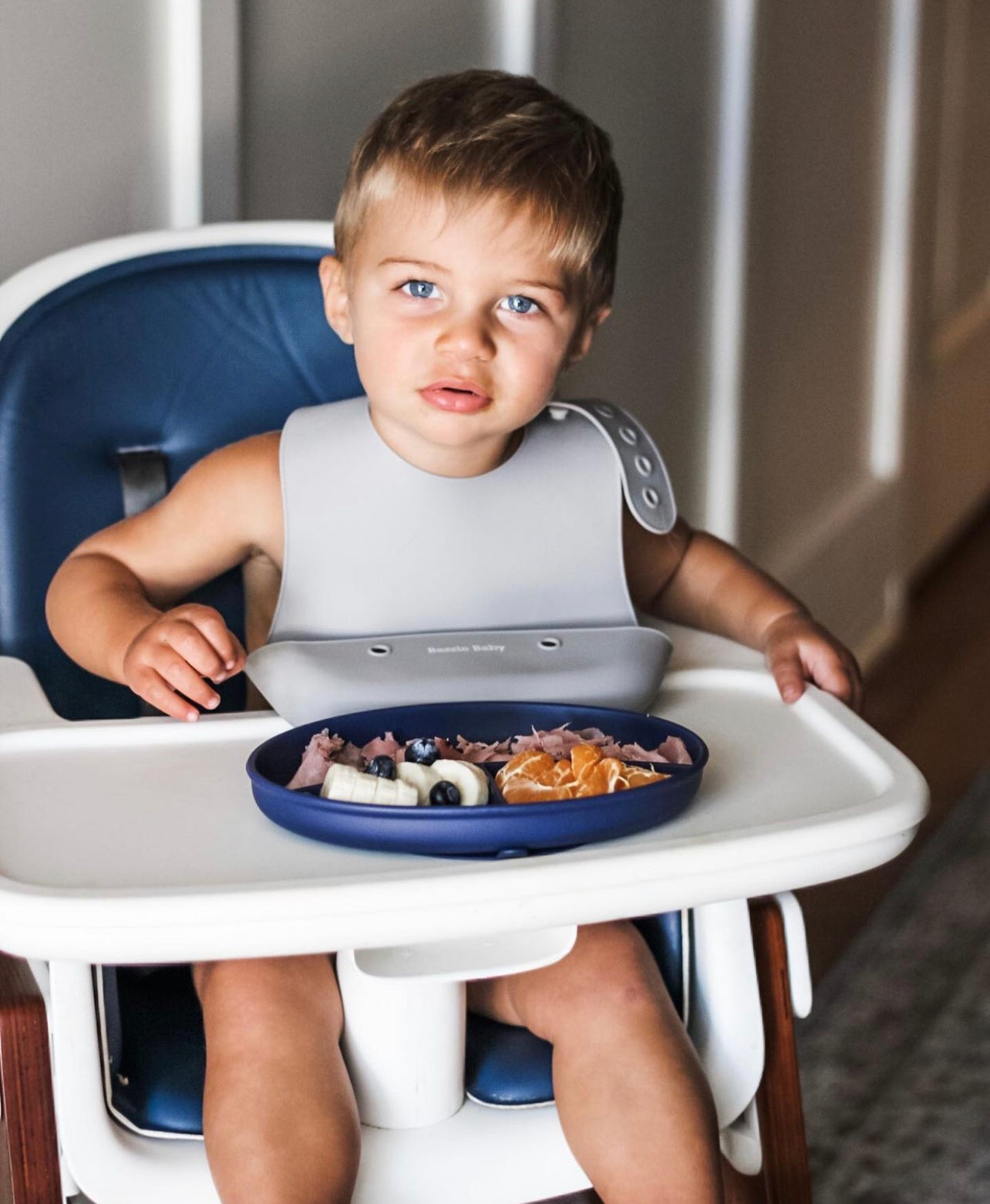 Baby wearing silicone bib with food catcher pocket. 